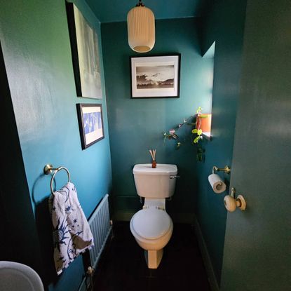 dark blue small bathroom with white toilet and gold fixtures