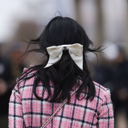 Susanna Lau seen wearing a pink tweed jacket with matching mini skirt, light blue cardigan, pink decorated Chanel bag, white tights, light blue high Chanel boots, outside Chanel Show, during the Womenswear Fall/Winter 2024/2025 as part of Paris Fashion Week on March 05, 2024 in Paris, France