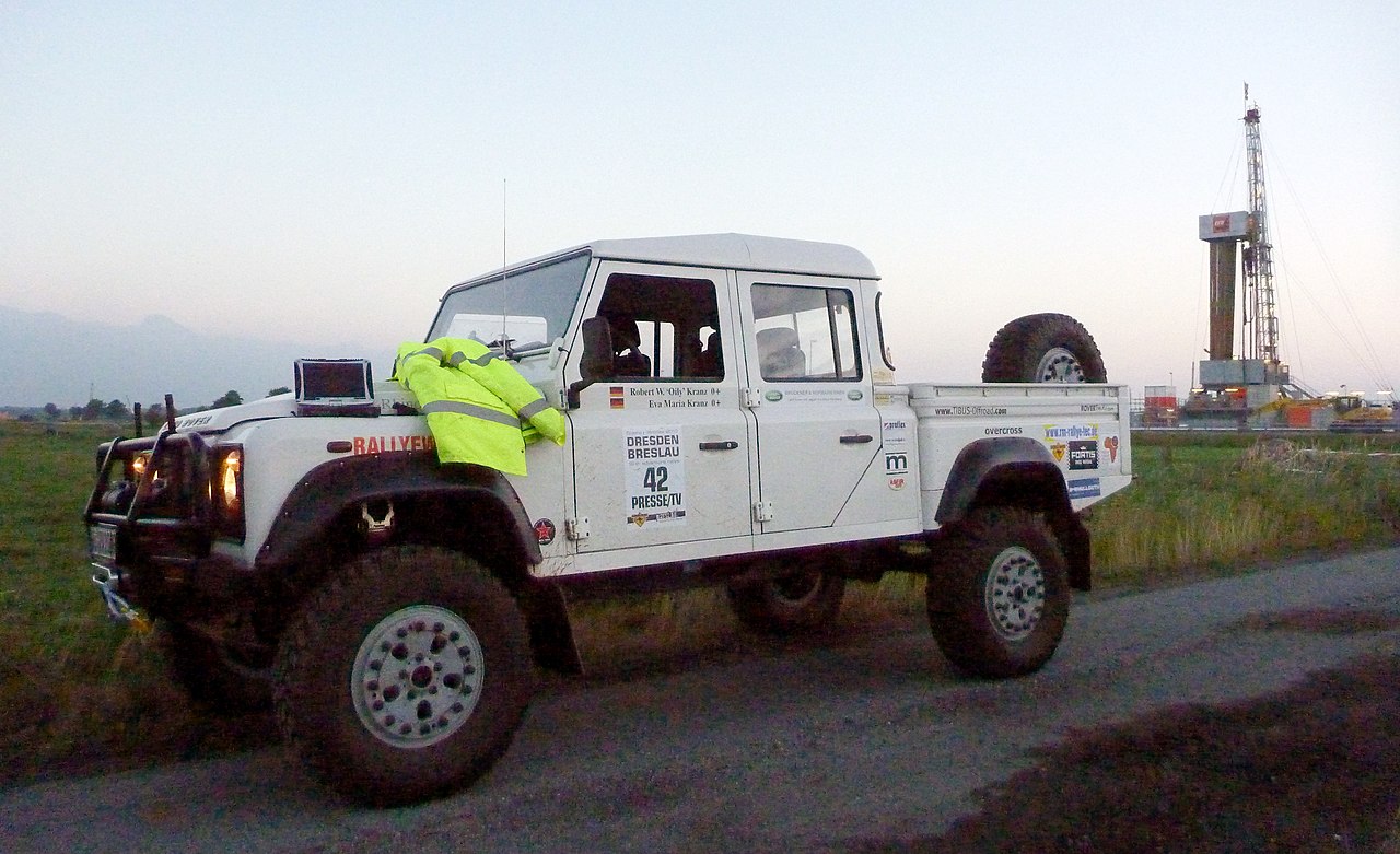 A Panasonic Toughbook on the hood of a Land Rover Defender, with a high-vis jacket next to it.