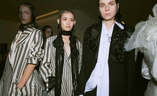 Models wear striped black and white blazers, and white shirt with black blazer