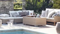 A rattan outdoor sofa set by the side of a pool