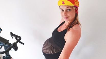 Female cyclist riding indoors on her bike whille pregnant