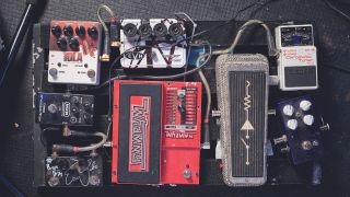 A worn, dirty pedalboard with a variety of different guitar pedals