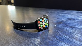 En Apple Watch 8 ligger på ett blått skrivebord.