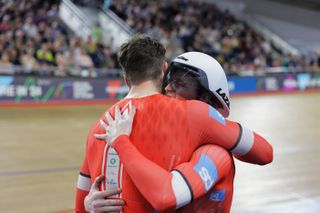 Two cyclists in red jerseys hugging
