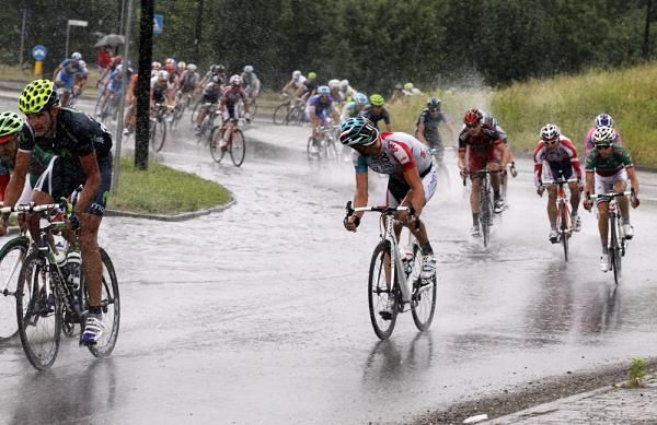 The peloton heads through a small lake caused by a downpour