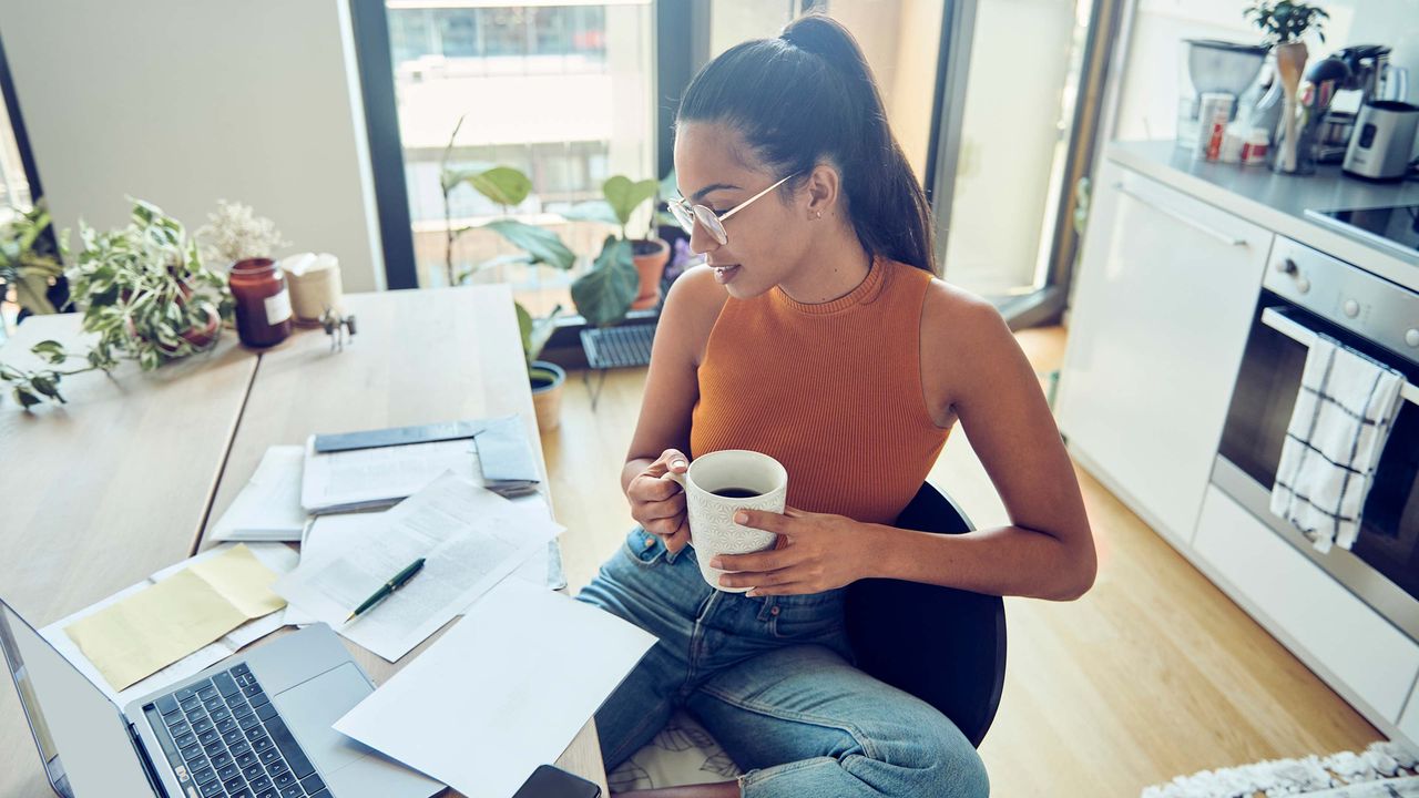 A woman cradles a cup of coffee as she works on her taxes.