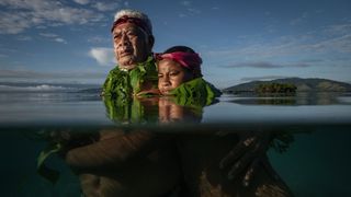 A Fijian community elder stands with his grandson at the point where he remembers the shoreline used to be when he was a boy in Salia Bay, Kioa Island, Fiji