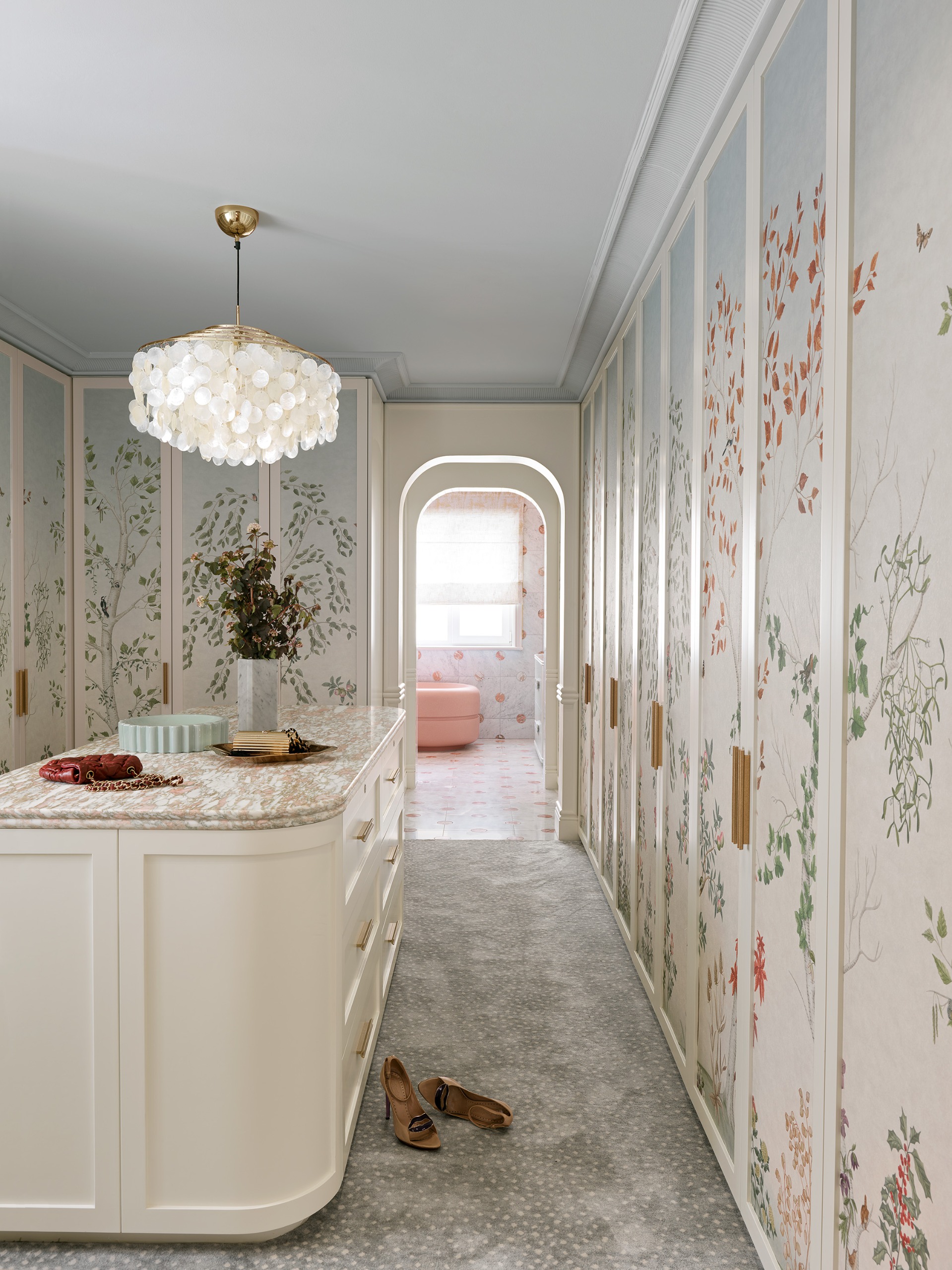 beautiful dressing room with painted cupboard and a capiz shell chandelier hanging over the central storage unit