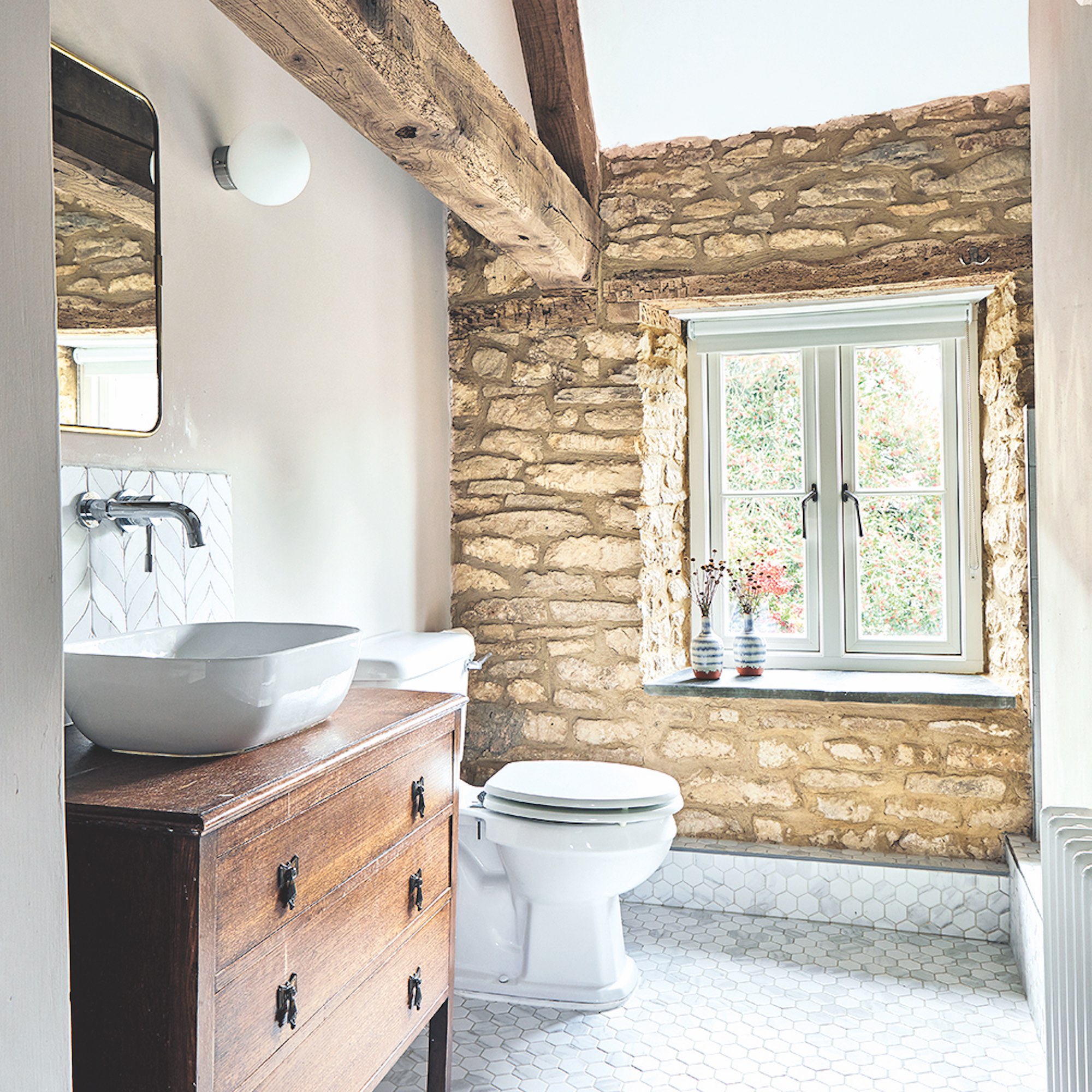 white bathroom with exposed stone wall and wooden vanity