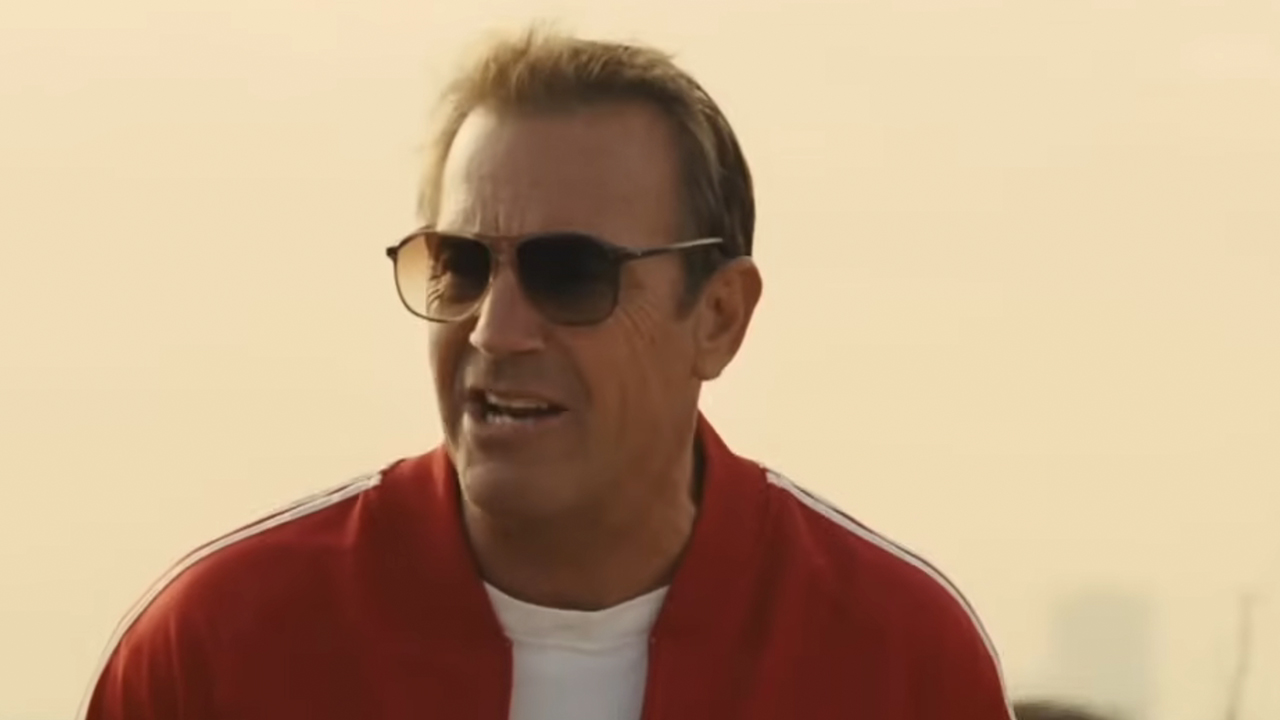 Kevin Costner wearing a red track suit and sunglasses in McFarland, USA