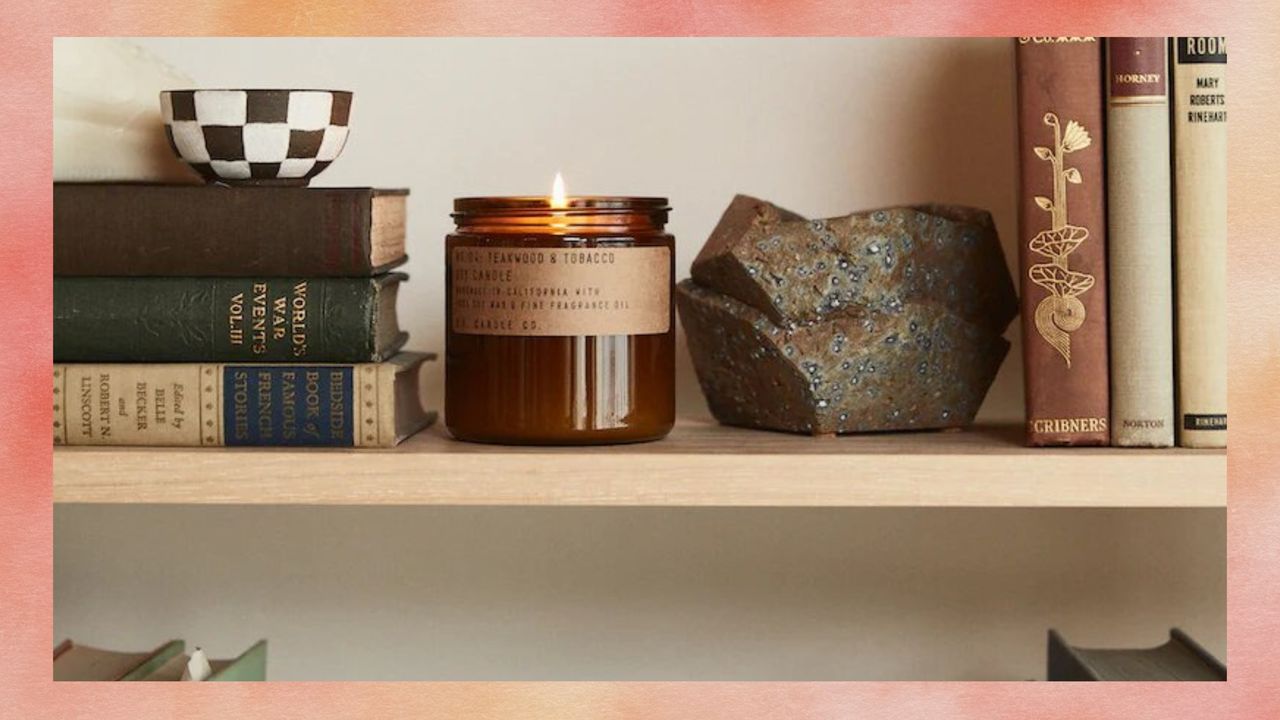 Candle sitting on a shelf with books and decor