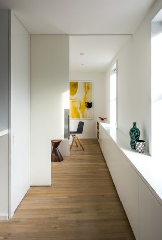 Hallway to home office with white walls and large pocket door