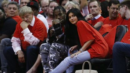 Travis Scott and Kylie Jenner sit court side at a basketball game.