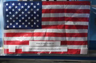 An American flag flown on the first and last space shuttle missions awaits the arrival of the first U.S. commercial crew to launch to the International Space Station. The small flag went missing for a time during its nine years aboard the orbiting laboratory.