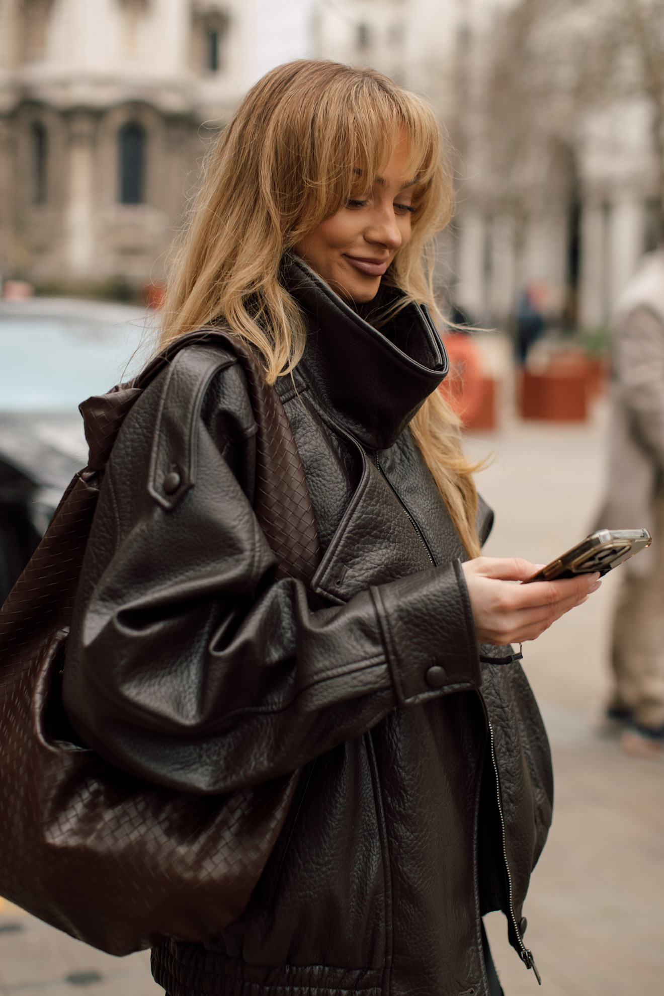 a woman in a black leather jacket with fluffy bangs