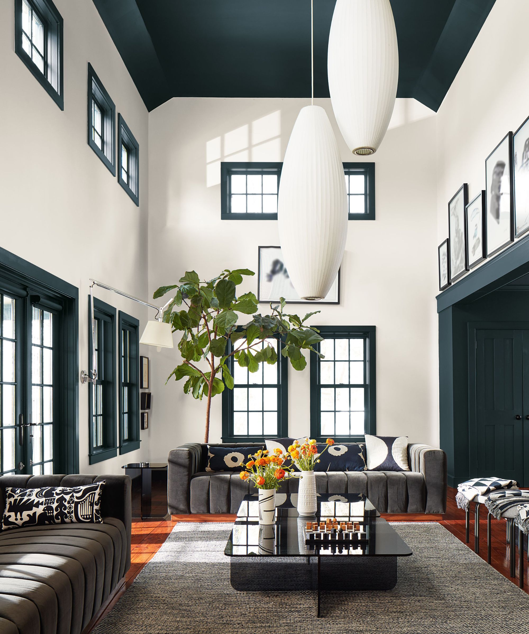 Statement living room with dark green window frames, high ceilings and mid-century styling, brought to life with bold contrast and graphic accents.