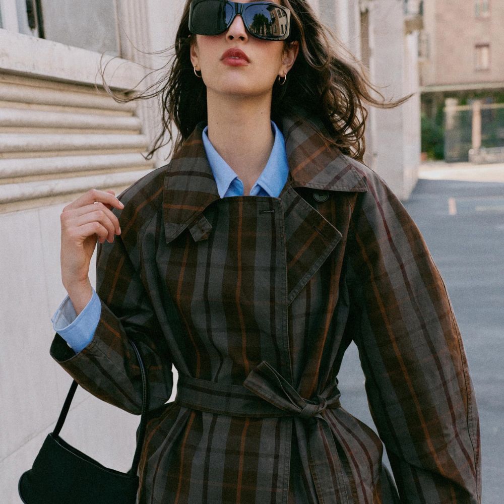 Woman with brown hair wearing checked jacket and sunglasses