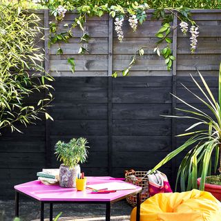garden area with grey fence and potted plants