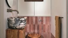 a small bathroom with pink tiles and a bold marble sink
