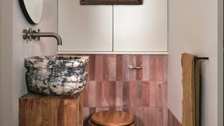 a small bathroom with pink tiles and a bold marble sink