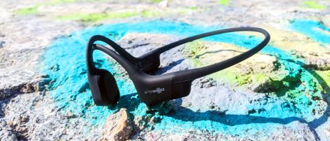 The Shokz OpenRun bone conduction headphones pictured on a stone surface