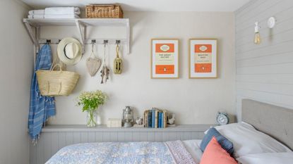 Small bedroom with grey wood panelling and bed with white, blue and orange bedding.