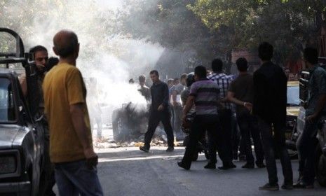 Iranians look on as a garbage can is set on fire in central Tehran on Wednesday, after the regime cracks down on black market currency trading.