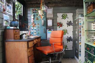 Cuprinol shed of the year: a home office with grey panelled walls, antique wooden desk and orange desk chair