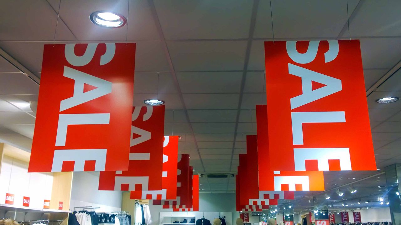 red sign with white &amp;quot;sale&amp;quot; letters hanging from store ceiling