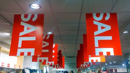 red sign with white "sale" letters hanging from store ceiling