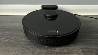 The Dreame Bot L10 Pro on its charger on a hard wood floor