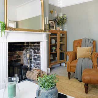 brick fireplace with gold framed mirror next to brown armchair