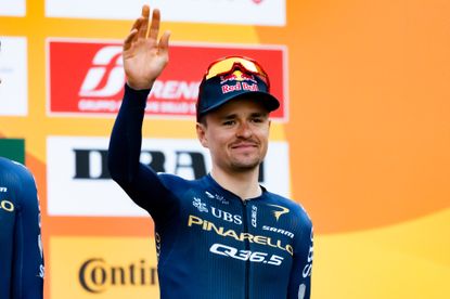 Tom Pidcock waves at a team presentation