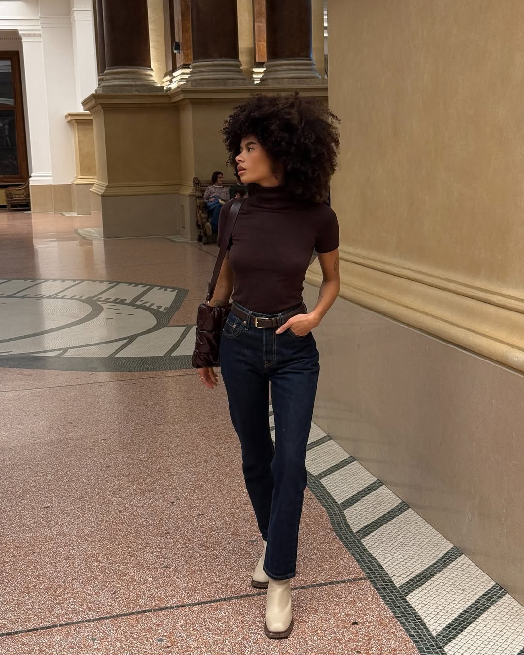 woman wearing fitted short-sleeve turtleneck with slim dark jeans and belt