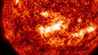 a bright white flare erupts from the fiery surface of the sun