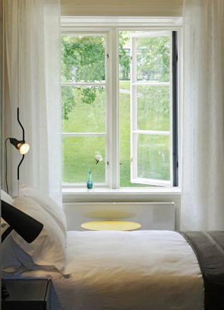 Hotel bedroom in white with open window to the garden