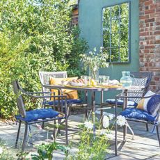 small garden patio with a metal furniture set in front of a green painted wall