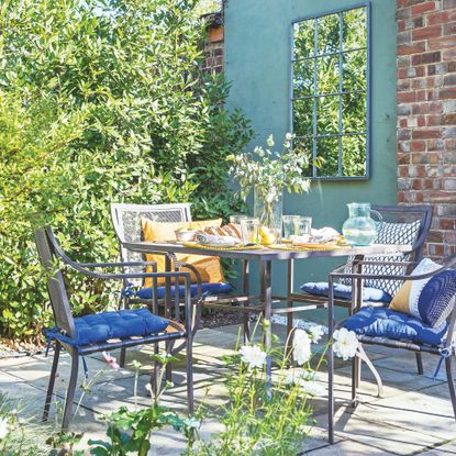 small garden patio with a metal furniture set in front of a green painted wall