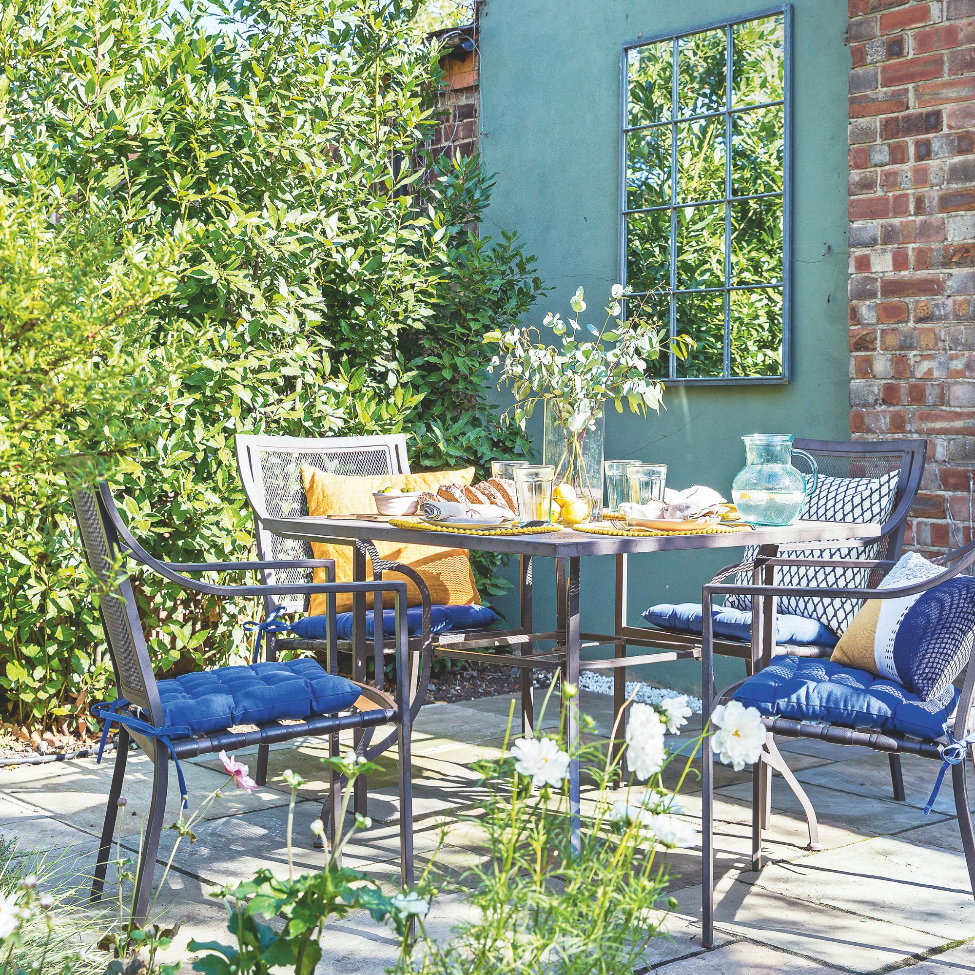 small garden patio with a metal furniture set in front of a green painted wall
