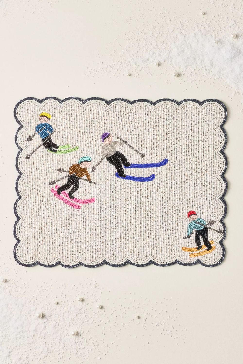 White beaded placemat with ski motif and scalloped edge