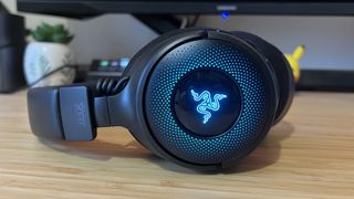 Razer Kraken V4 with blue RGB on laying sideways on a wooden desk