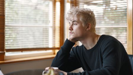 A young man looks thoughtful as he looks out the window.