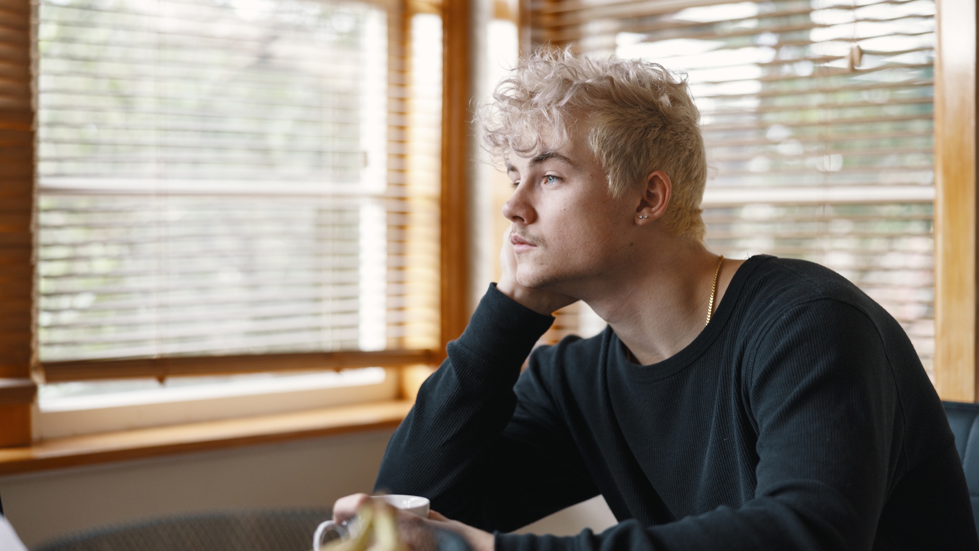 A young man looks thoughtful as he looks out the window.