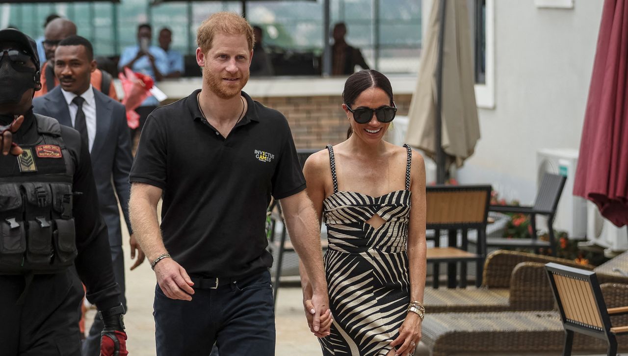 Meghan Markle and Prince Harry walk in Nigeria while Meghan Markle wears a mostera printed dress