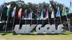 A LIV Golf sign in front of flags showing the team logos