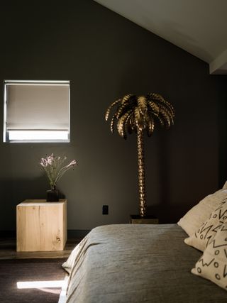 A bedroom with dark gray walls and light gray bedding