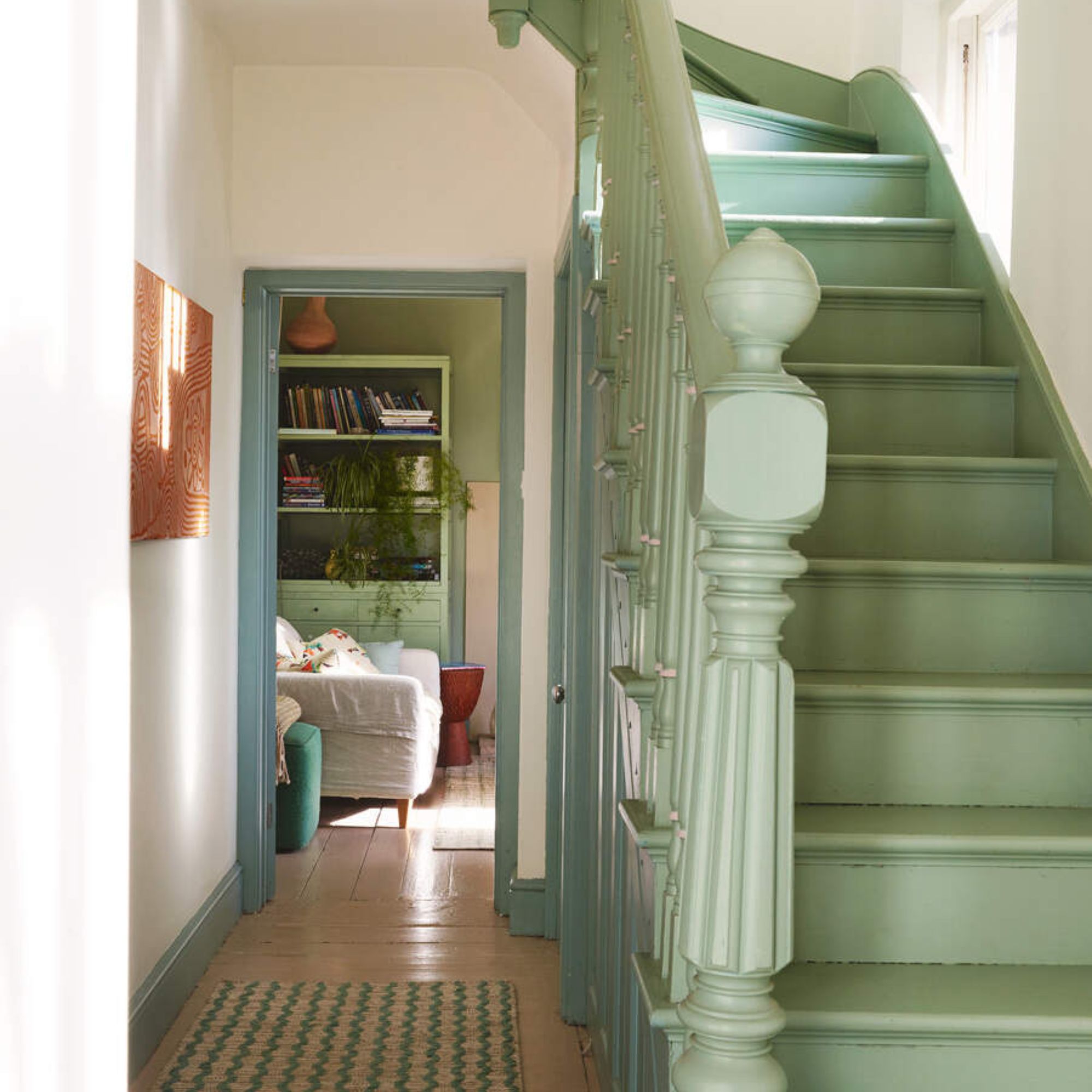 White painted halleway with green painted wooden stairs and green skirting boards