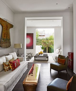 White living room paint ideas with red accents in the cushions and wall art.