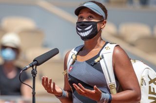Naomi Osaka of Japan conducts an on court interview wearing a mask after her victory against Patricia Maria Tig of Romania in the first round of the Women's Singles competition on Court Philippe-Chatrier at the 2021 French Open Tennis Tournament at Roland Garros on May 30th 2021 in Paris, France.